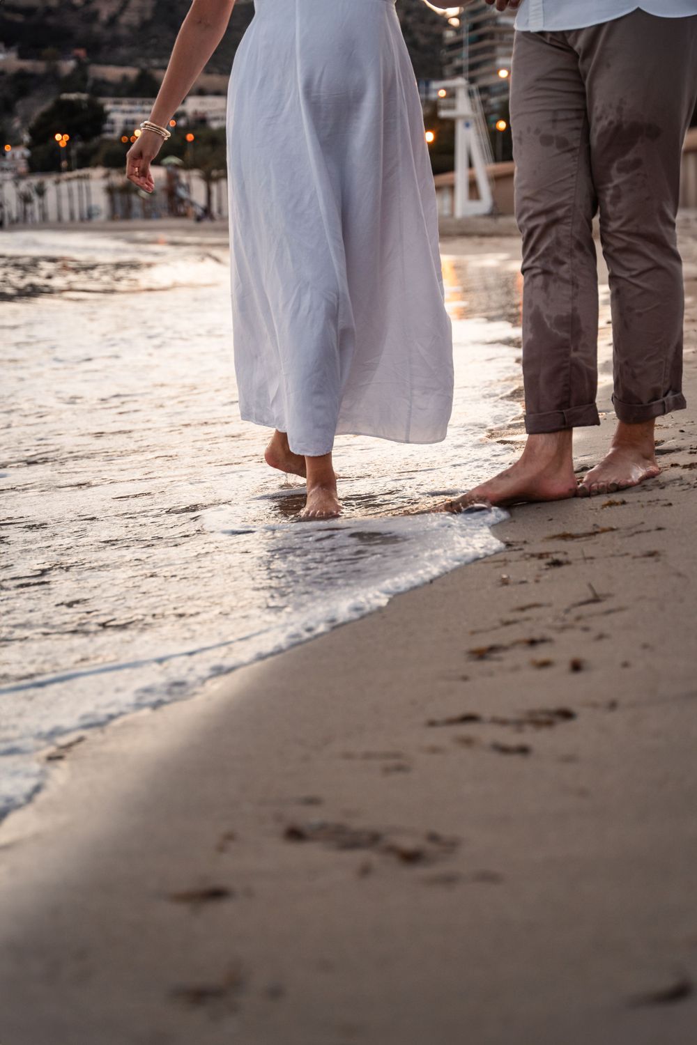 detail photo of couple walking on the sand and their footprints in the sand