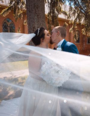 A bride and groom share an intimate moment under pine branches during their wedding photoshoot.
