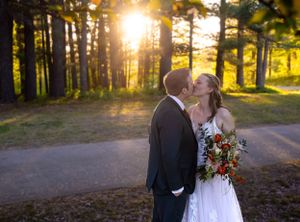 Romantic sunset wedding portrait in forest with couple kissing.