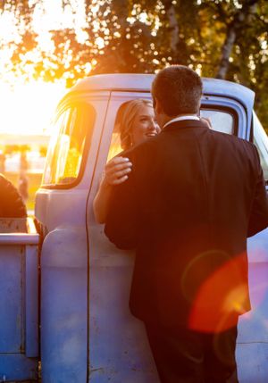 Romantic sunset silhouette of couple by vintage truck during golden hour.