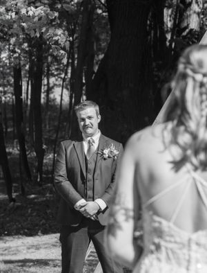 Black and white first look moment between couple in wooded setting.