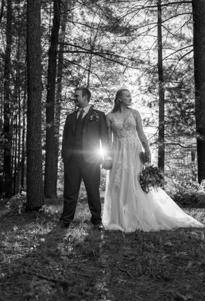 Dramatic black and white forest wedding portrait with sunburst.