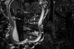 Artistic black and white reflection of wedding couple in ornate vintage mirror.
