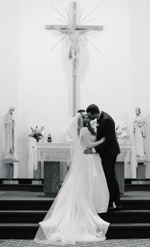 Black and white photo of a wedding ceremony in a church with a large crucifix on the wall.