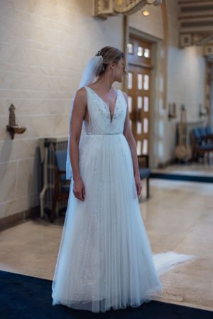 Detail shot of flowing white wedding dress with lace bodice in church hallway.