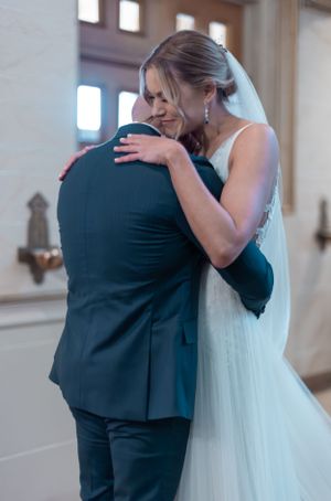 Emotional embrace between wedding couple as they share their first reaction at an indoor venue.