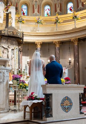 Beautiful church ceremony with an ornate altar decorated with colorful flowers and stained glass windows.