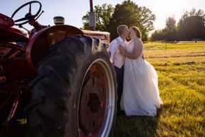 Romantic sunset wedding photos with antique farm equipment silhouetted in golden field.