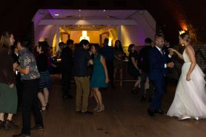 Wedding reception dance floor with guests dancing and celebrating under warm lighting.
