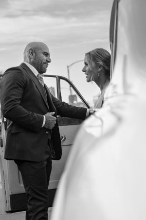 Black and white photo of couple entering their wedding transportation vehicle.