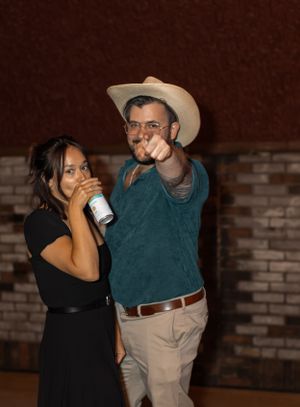 Casual dance partners enjoying a moment at evening reception with brick wall backdrop.