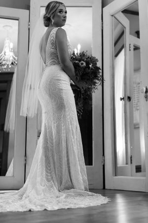 Elegant lace wedding dress with open back detail and flowing train photographed in black and white.