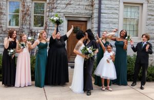 Wedding party celebrates with couple on stone building steps.