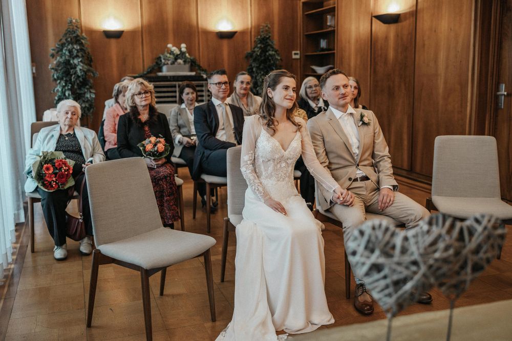 Wedding ceremony venue with wood paneled walls and seated guests in formal attire.