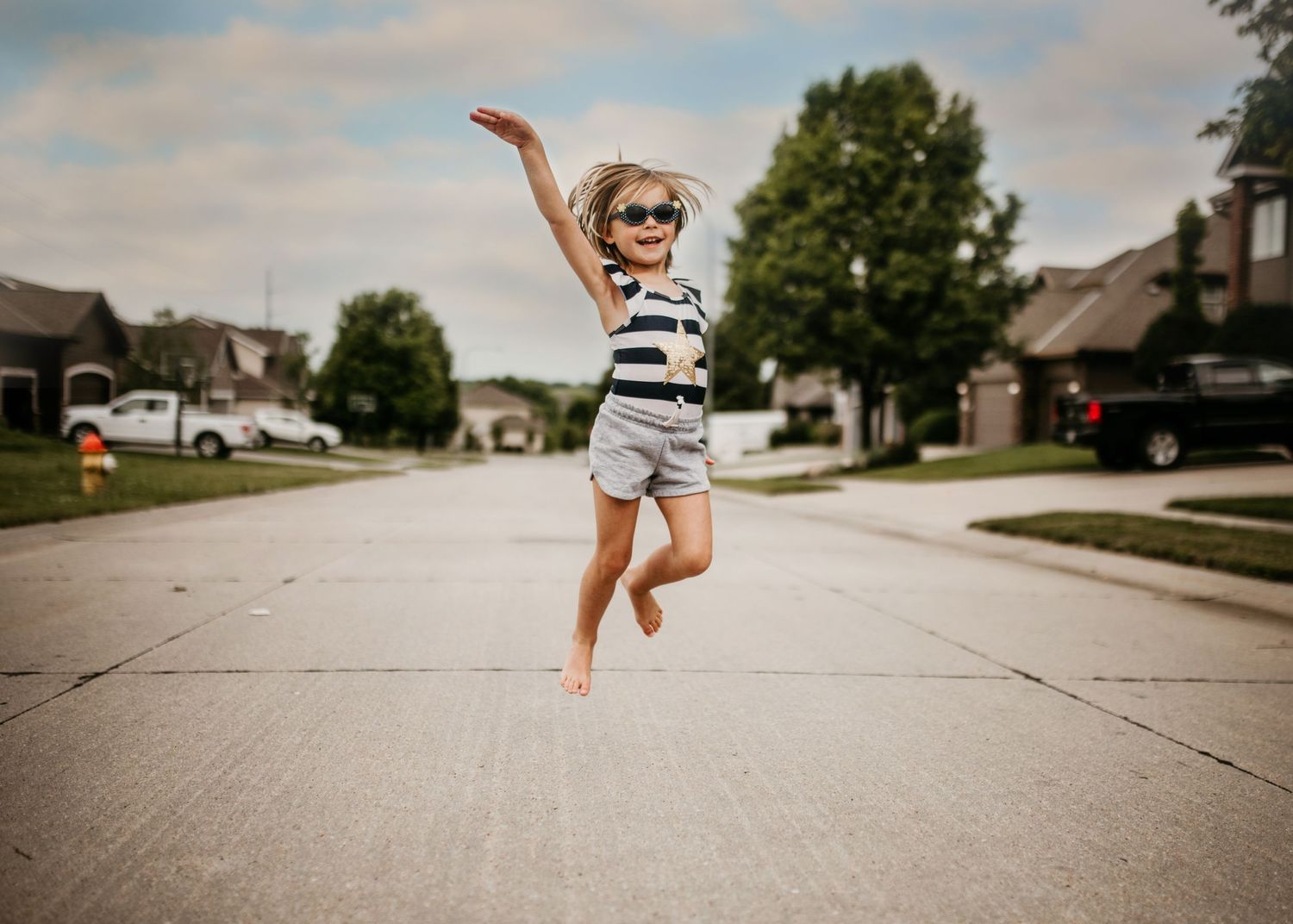 Little girl jumping with joy wearing sunglasses in Nebraska