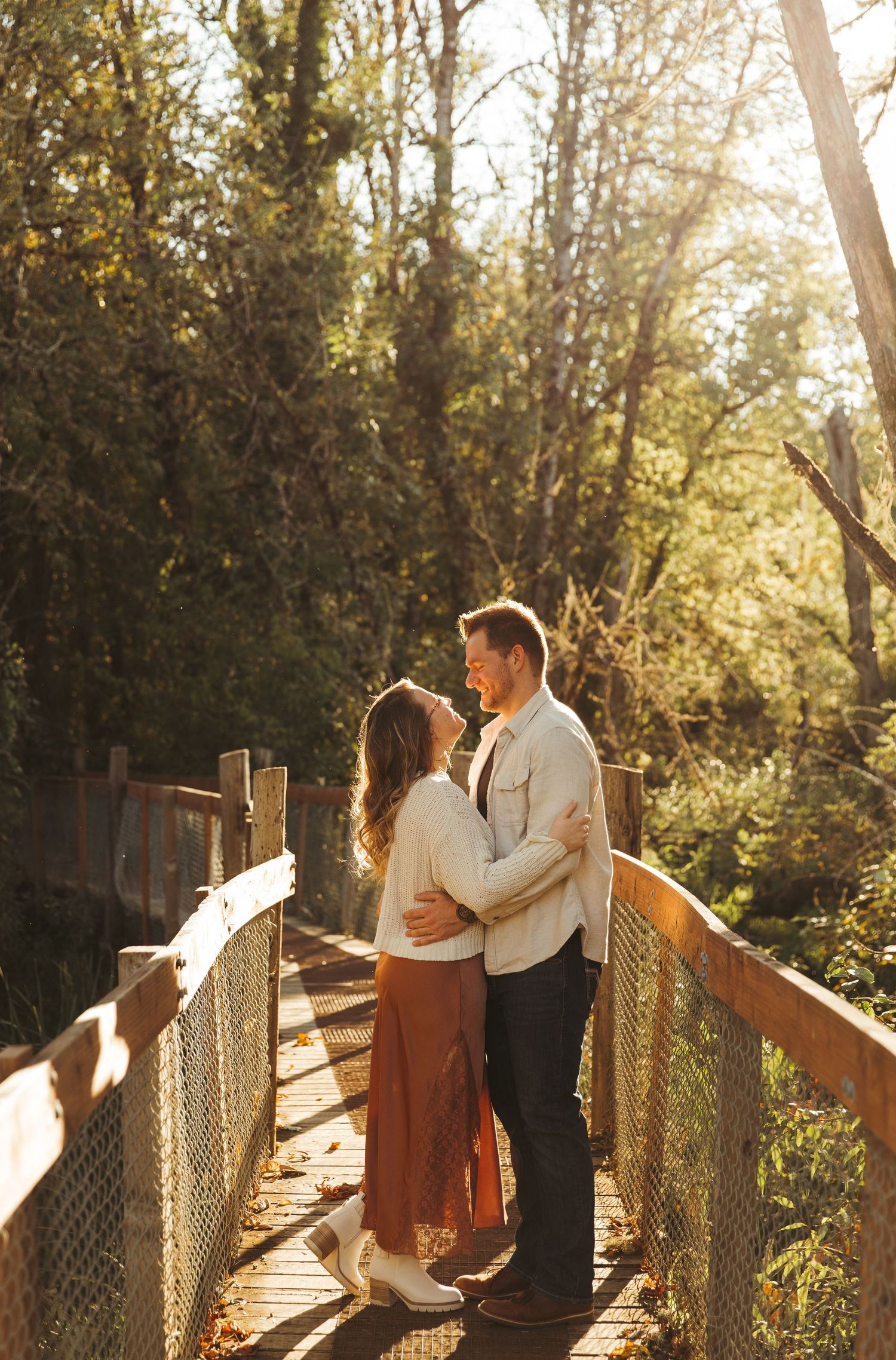 Romantic lakeside moment between two people at sunset with evergreen trees in background.
