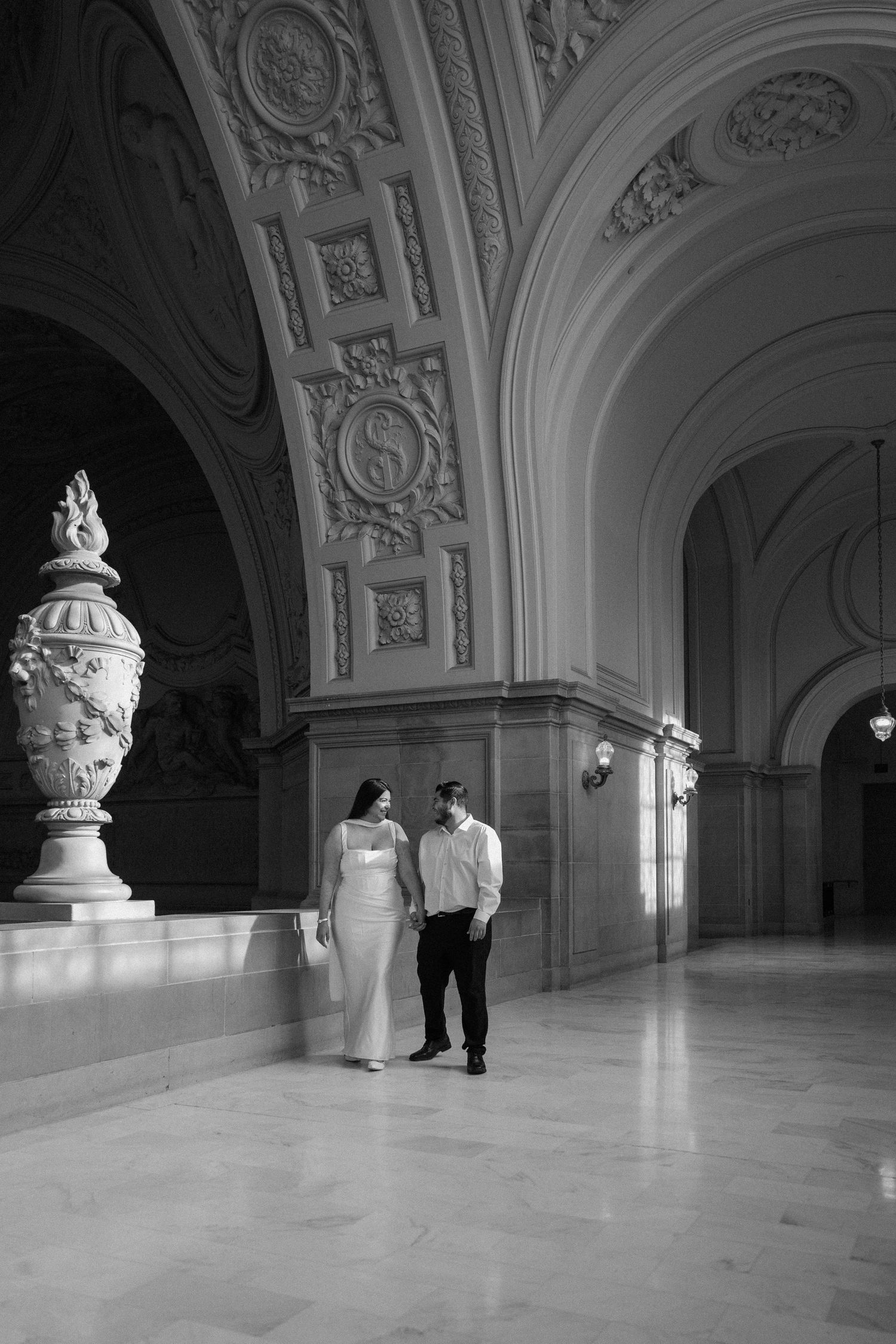 A photographer in a floral dress holds a camera while standing in green rolling hills in Antioch, CA.