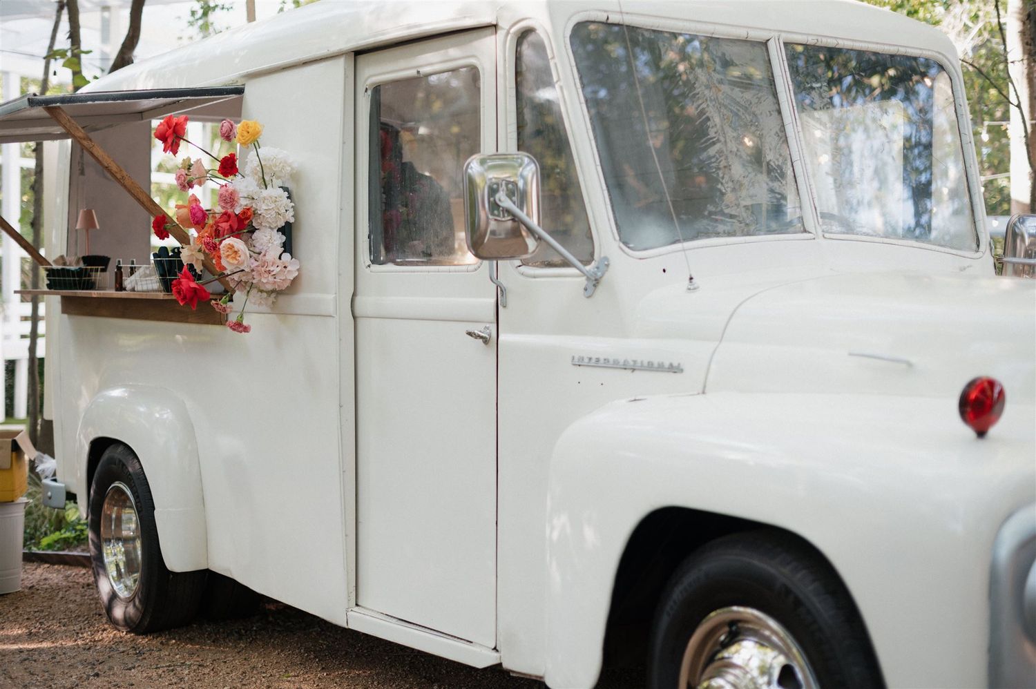 Vintage white truck decorated with flowers for a wedding event.