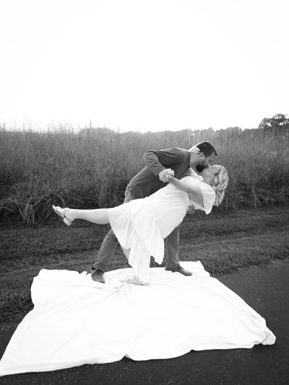 Couple dance on a blanket outdoors.
