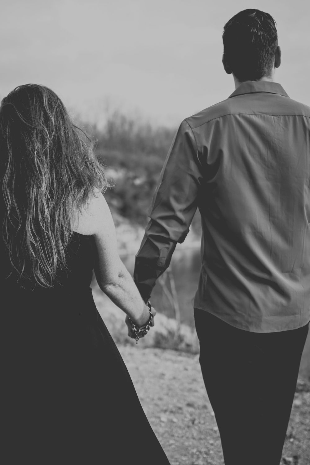 Black & White image of couple holding hands walking away.