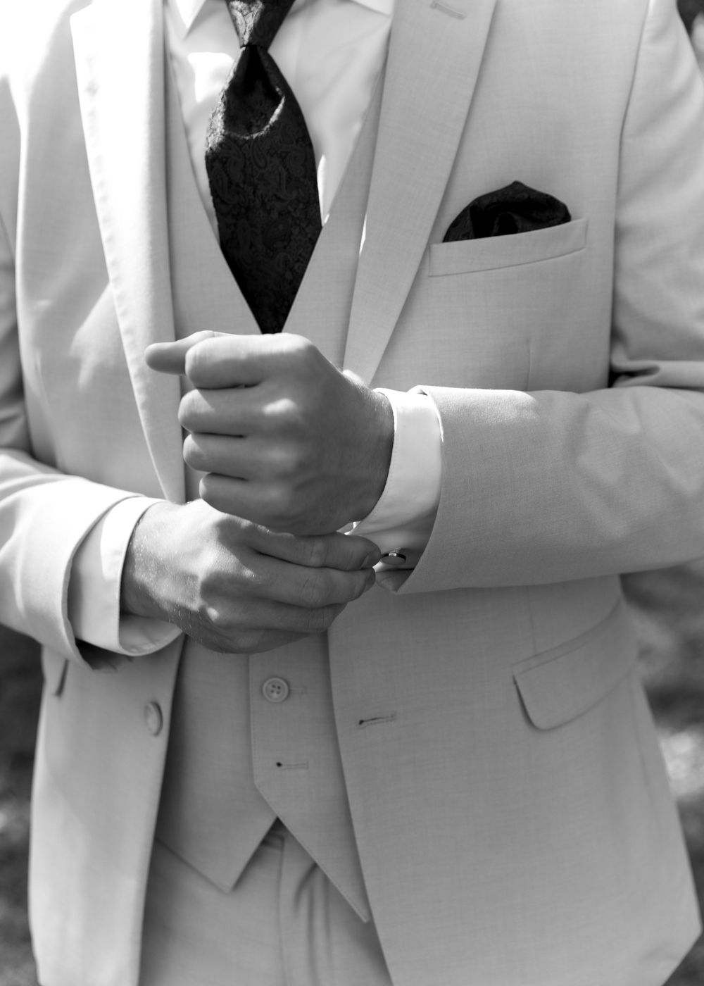 Detail shots of a light colored three-piece suit with black tie and boutonniere.
