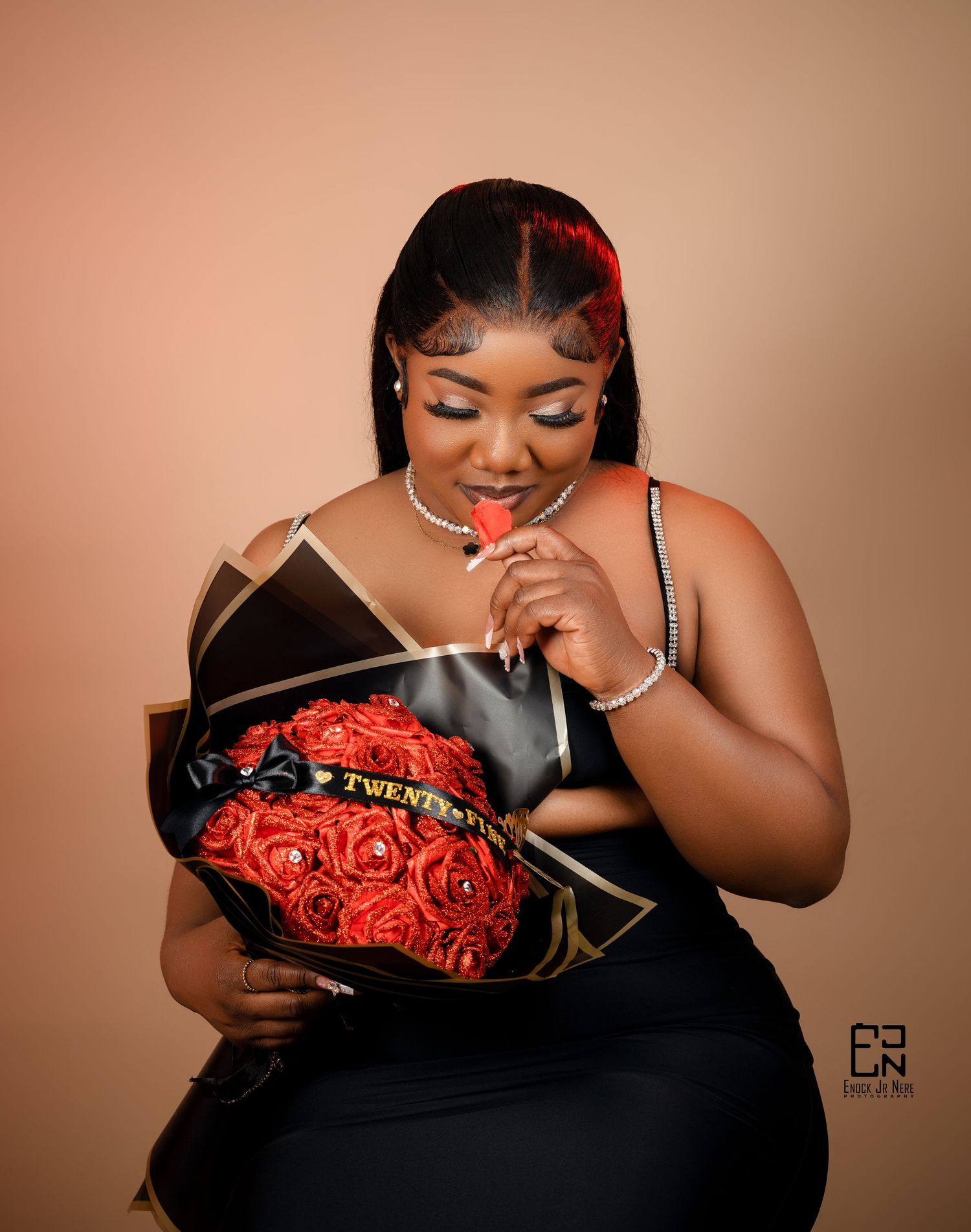 Glamour portrait with luxurious box of red roses against peachy background.