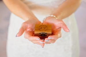 Hands holding a small wooden ring box with custom engraving.