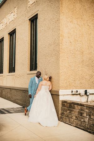 A sequence of wedding photos showing a couple walking together along a beige stone wall at their venue.
