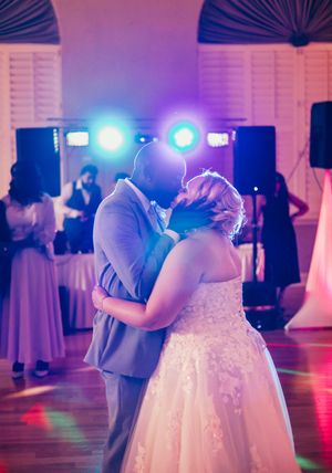 Wedding couples dancing in a ballroom under purple and blue lighting with white decor visible in background.