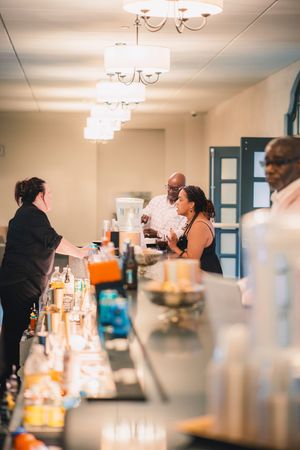 Blurred interior scene of a busy bar or restaurant with patrons and staff moving around under pendant lighting.