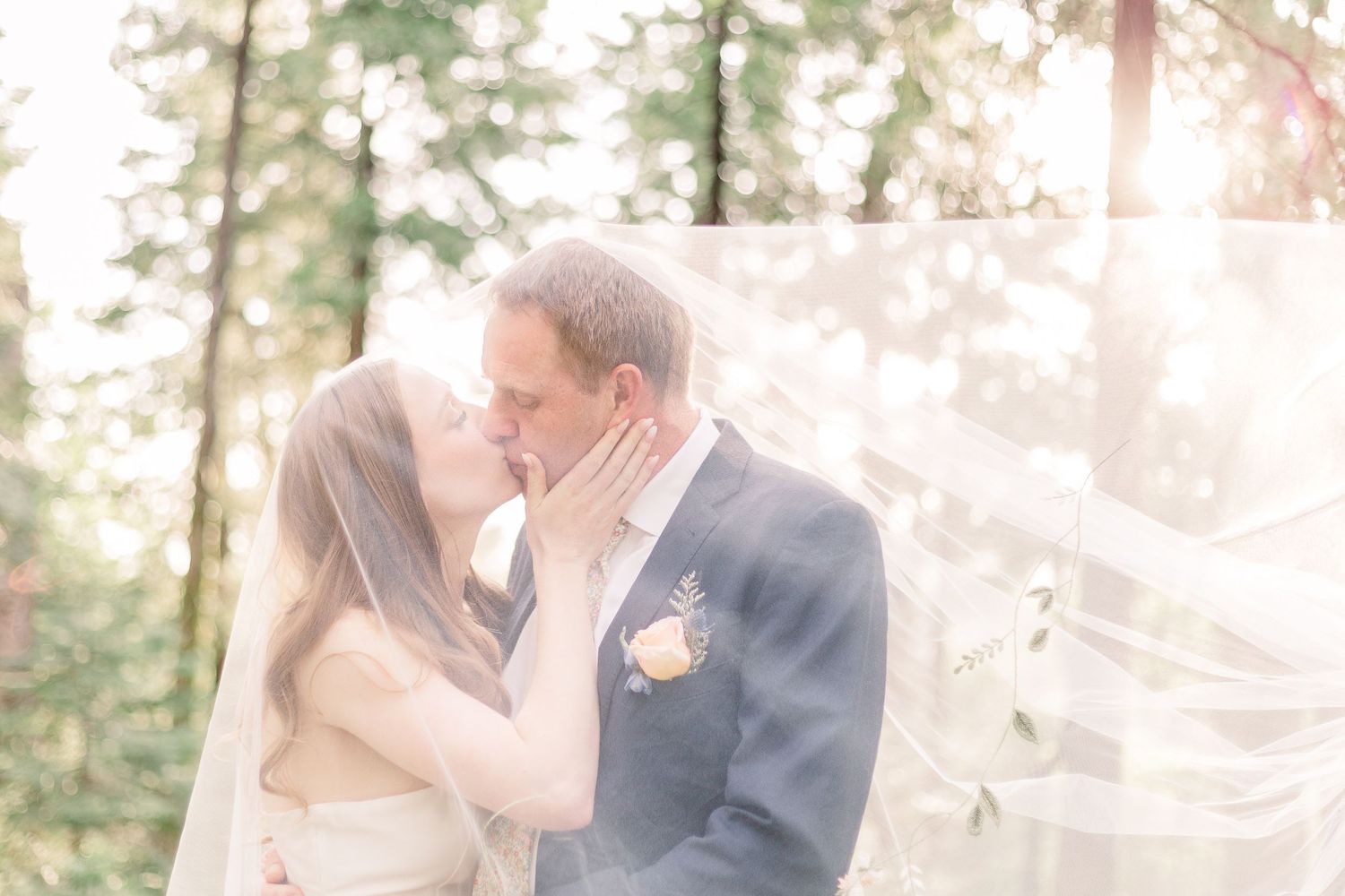 Romantic wedding couple embracing in sunlit forest setting.