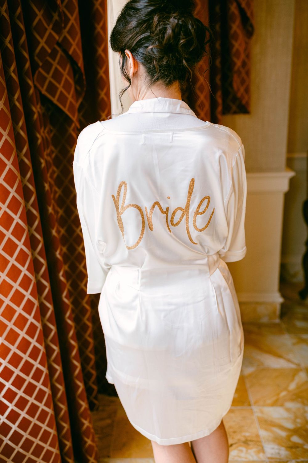 White satin robe with gold 'Bride' lettering shown from behind.