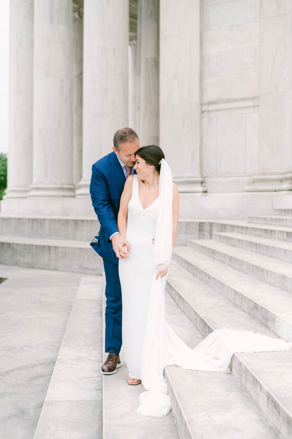 Intimate wedding portrait on white marble steps with classical columns.