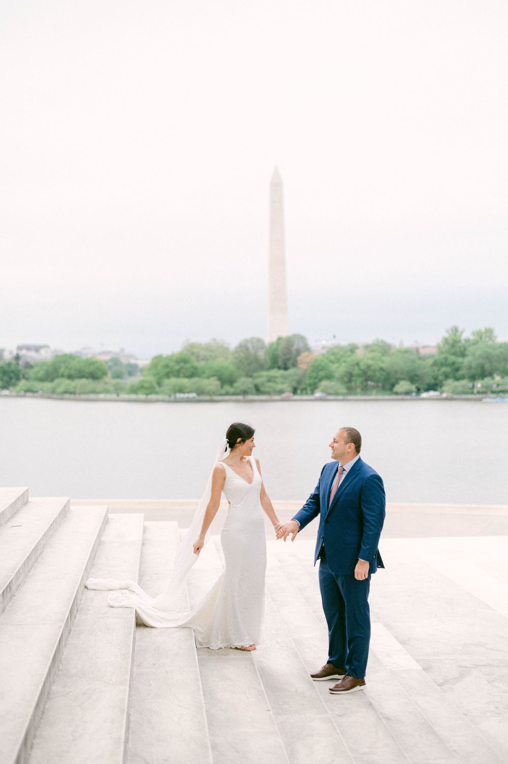 Wedding couple holding hands with Washington Monument in background.