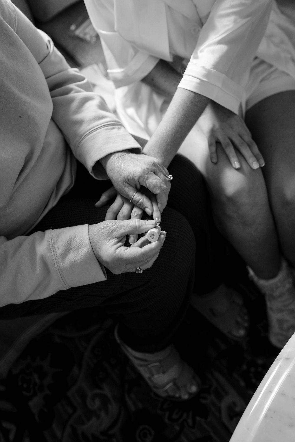 Close-up black and white shots of hands holding wedding rings during a ceremony.