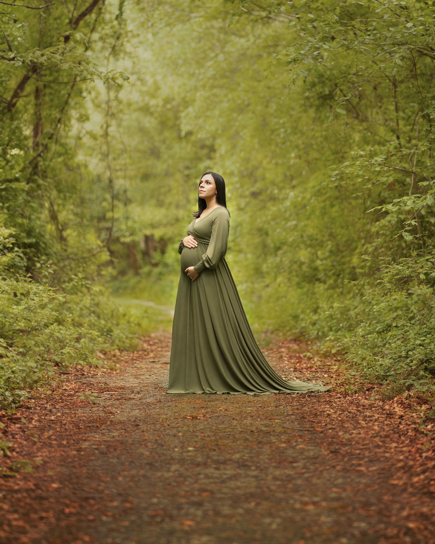Ethereal portrait in olive green gown on autumn forest path.