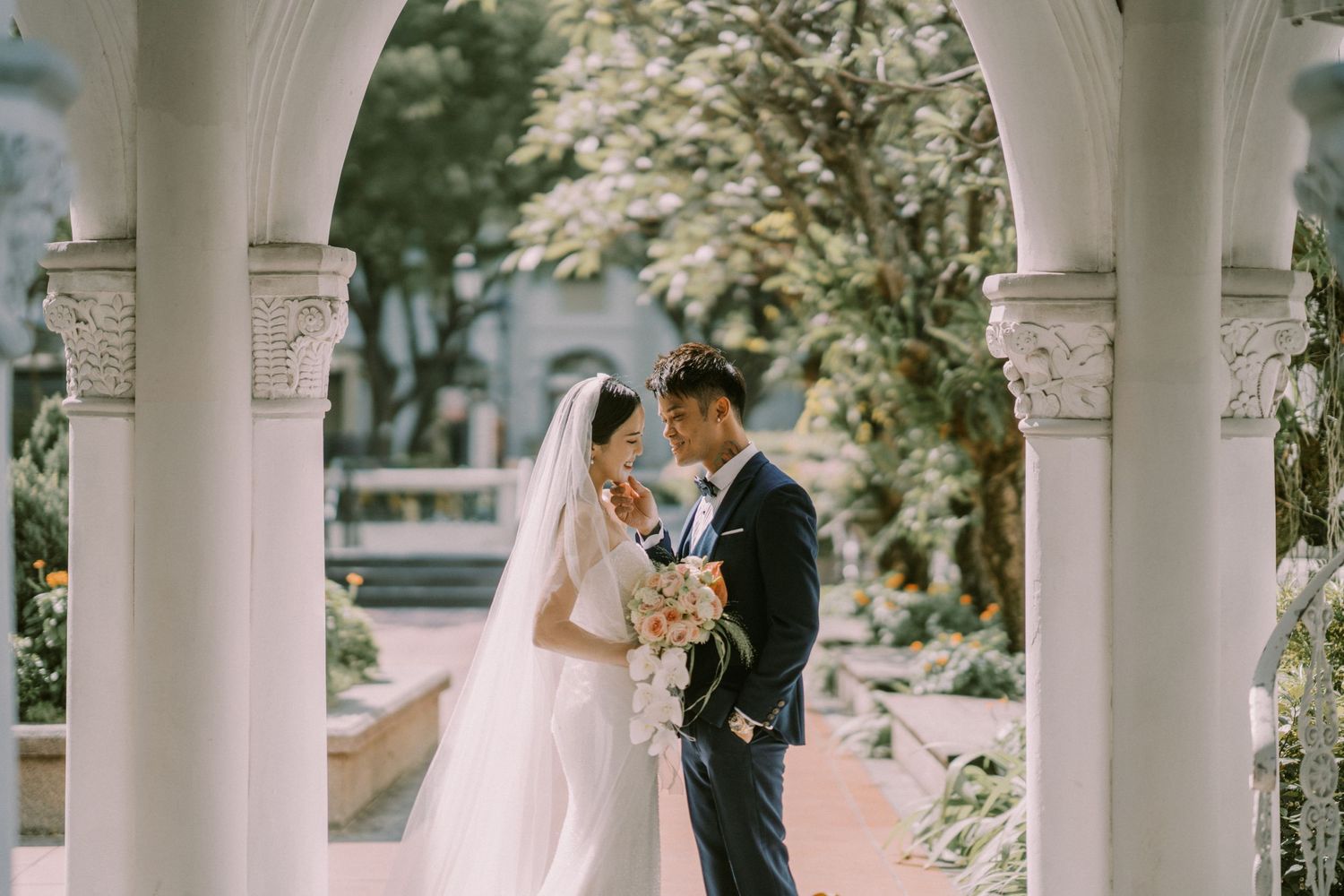 Romantic wedding couple sharing intimate moments under elegant white archways.