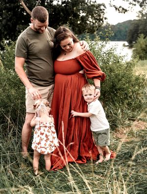 Family photo session in tall grass with lake view in background.