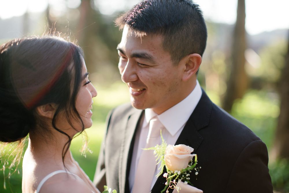 Candid portrait of happy couple in wedding attire sharing joyful moment outdoors.