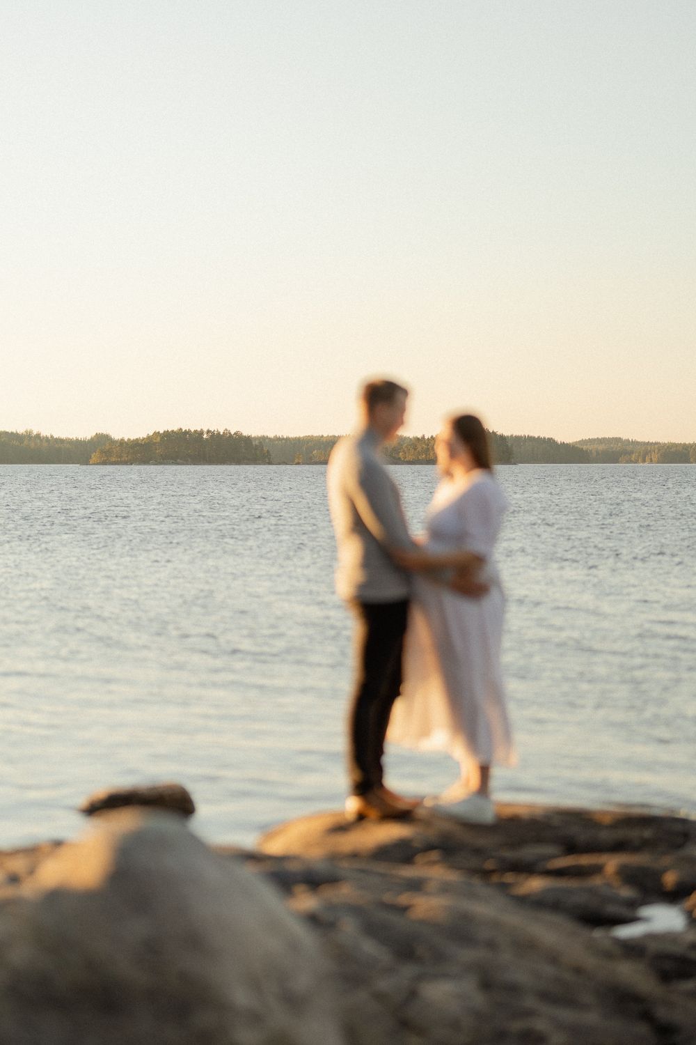 Pariskunta kalliolla järven äärellä