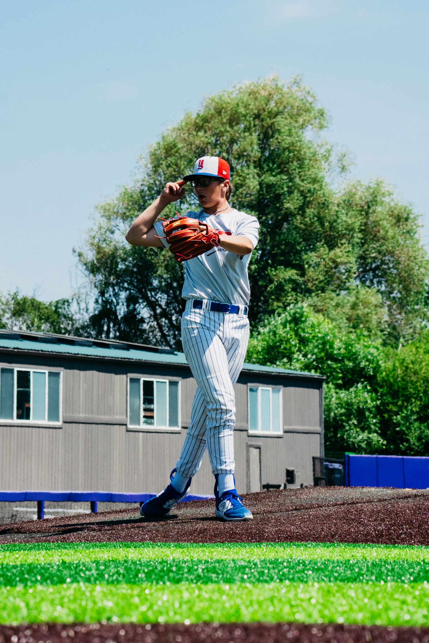 Baseball player in pinstripe uniform winding up for a pitch on the mound.
