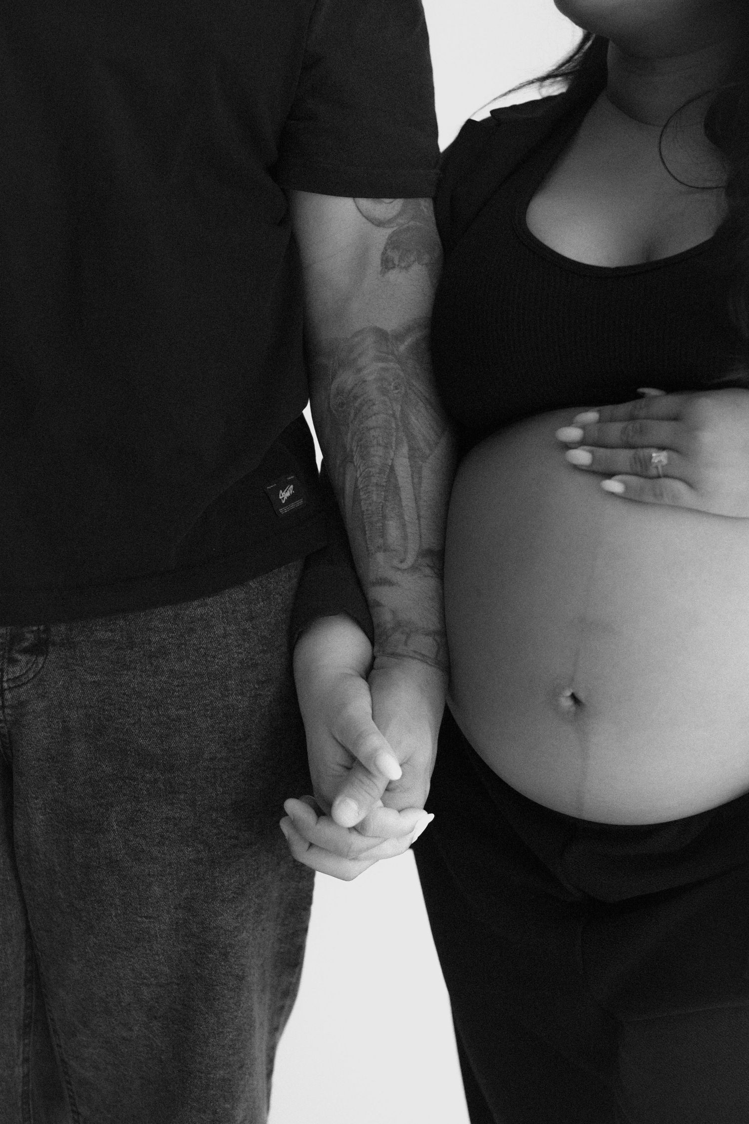 An intimate black and white maternity photo with a couple sharing a tender moment.