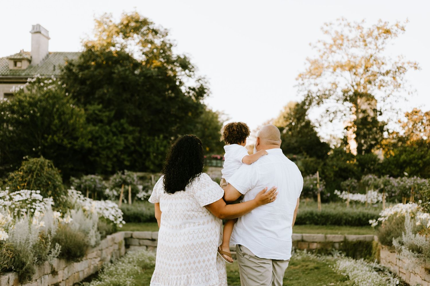 Family embracing while looking at sunset in a beautiful garden setting.