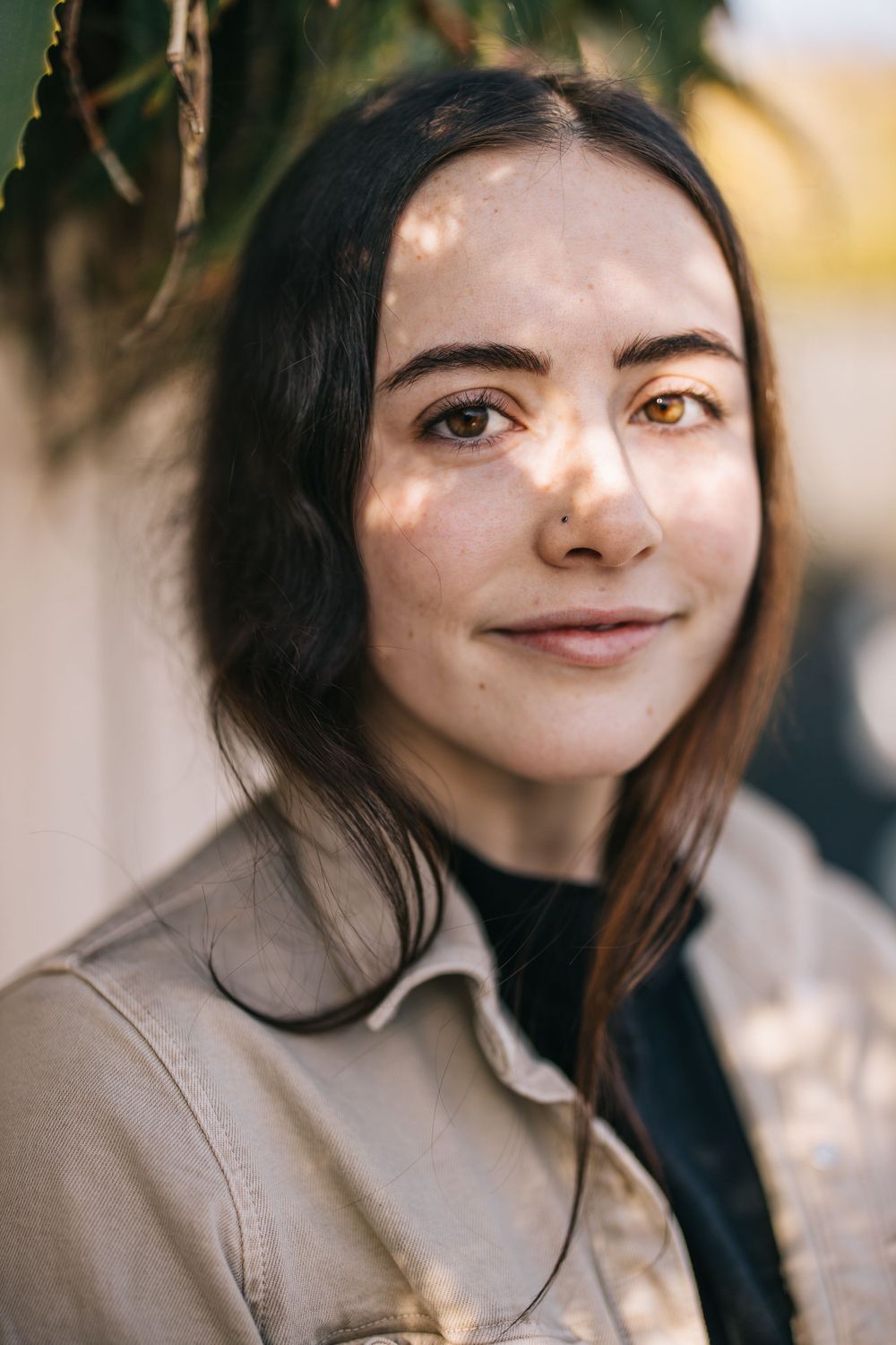 Portrait in beige jacket with natural lighting and soft background blur.