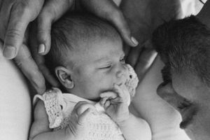 Black and white close-up of parents gazing at their baby wearing lace.