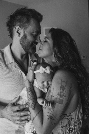Black and white intimate portrait of parents embracing with their sleeping baby.