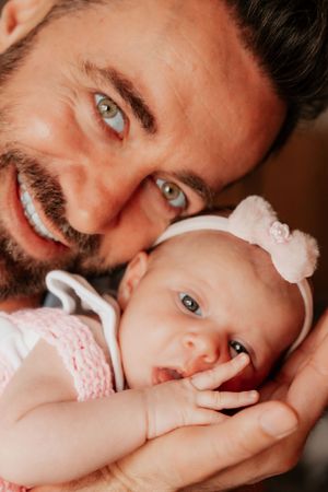 Close-up portrait of parent and baby with matching blue eyes and white bow accessory.