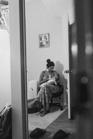 A black and white photo of a person sitting in a chair holding a newborn baby.