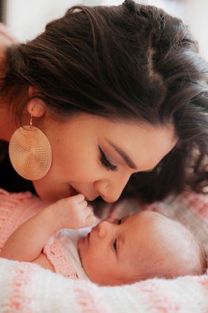 Tender moment between parent and infant on pink bedding.