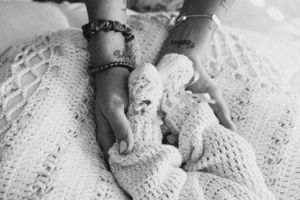 Black and white image of hands wearing bracelets holding delicate lace fabric.